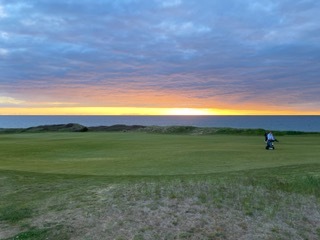 Miles walking the course with his push cart at sunset on the Nova Scotia coast